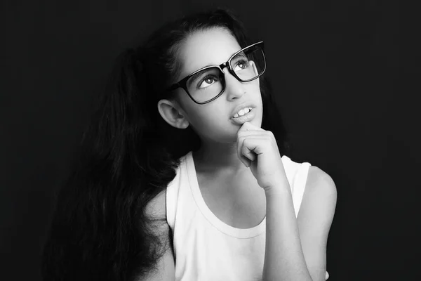 Menina adorável estudando com óculos em fundo preto — Fotografia de Stock