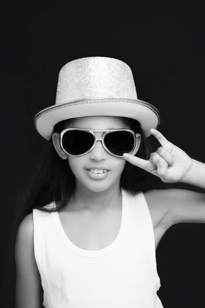 Menina roqueiro com óculos de sol e chapéu em um fundo preto — Fotografia de Stock