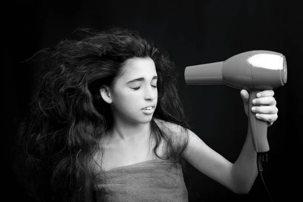 Menina vestindo uma toalha secando o cabelo com um secador de cabelo em preto — Fotografia de Stock