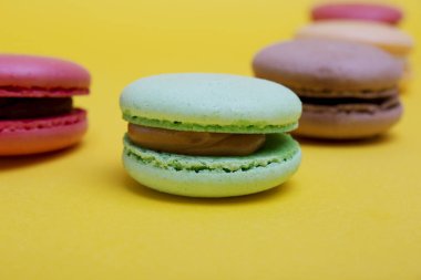 Tasty farklı macarons sarı arka plan üzerinde renkli