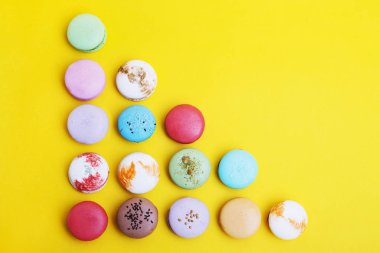 Tasty farklı macarons sarı arka plan üzerinde renkli