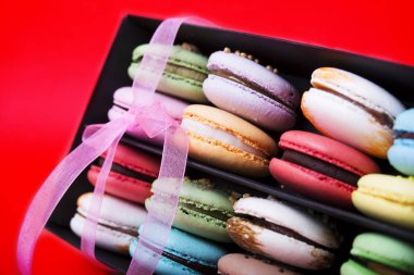 Tasty farklı macarons kara kutu kırmızı bir arka plan üzerinde renkli