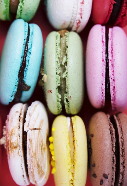 Tasty different colored macarons on red background — Stock Photo, Image