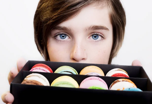 Junge hält Nachtisch-Macarons in schwarzer Holzkiste — Stockfoto