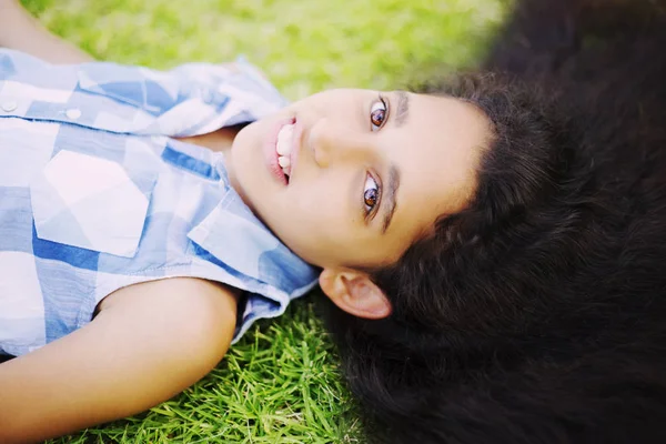 Pretty girl with long brunette hair lying on green grass — Stock Photo, Image