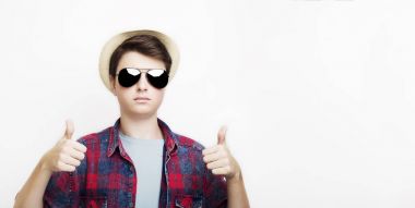 Yakışıklı erkek güneş gözlüğü ve şapka ile başparmak gösterilmesini
