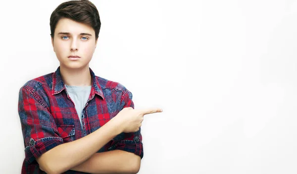 Look over there! Young handsome man in jeans shirt pointing away while standing against white background — Stock Photo, Image