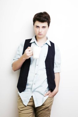 Emin yakışıklı delikanlı fincan sıcak bir içecek ile tutan kot gömlek