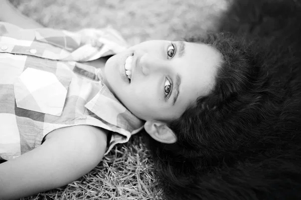 Güneşli günde yeşil çim üzerinde yalan uzun esmer saçlı güzel kız