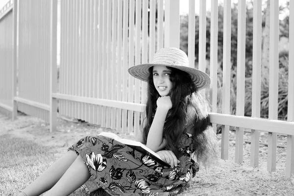 Menina adorável em vestido e chapéu livro de leitura . — Fotografia de Stock