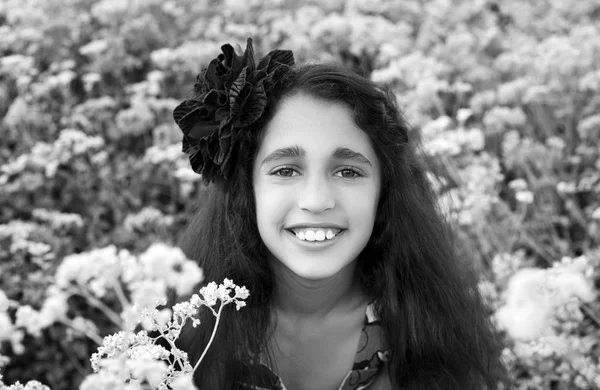 Menina bonito no parque com as primeiras flores selvagens brancas . — Fotografia de Stock