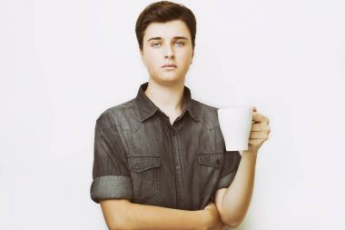 Kahve molası. Emin yakışıklı delikanlı fincan sıcak bir içecek ile tutan kot gömlek