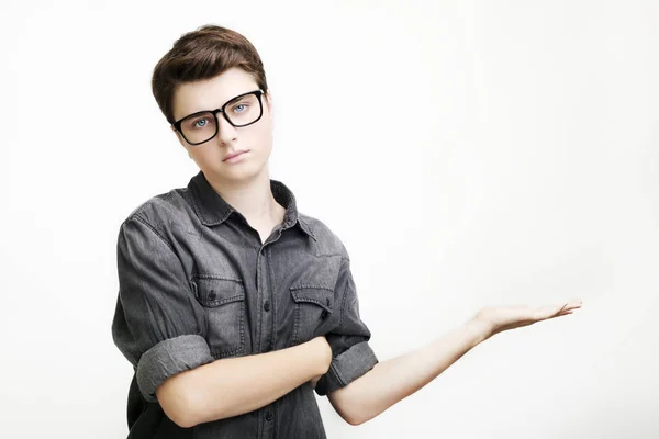 Young handsome man in glasses and jeans shirt pointing away while standing against white background — Stock Photo, Image