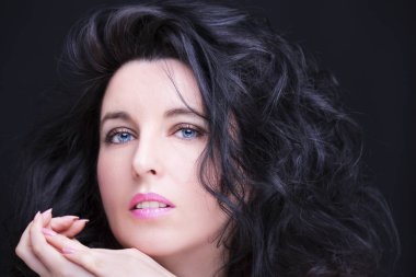 Uzun siyah saçlı, esmer, çekici bir kadın..