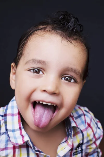 Speelse jongetje zijn tong met lachende ogen uitsteekt — Stockfoto