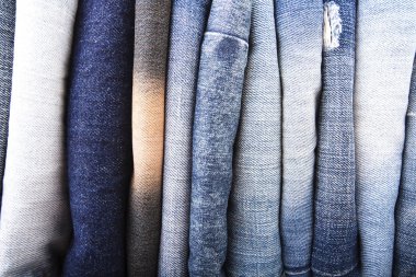 Beyaz arka plan üzerinde koyu mavi kot pantolon, kot pantolon ve katlanmış giysi yığını