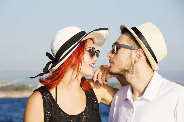 Beautiful couple of lovers sailing on a boat. Two fashion models posing on a sailing boat at sunset