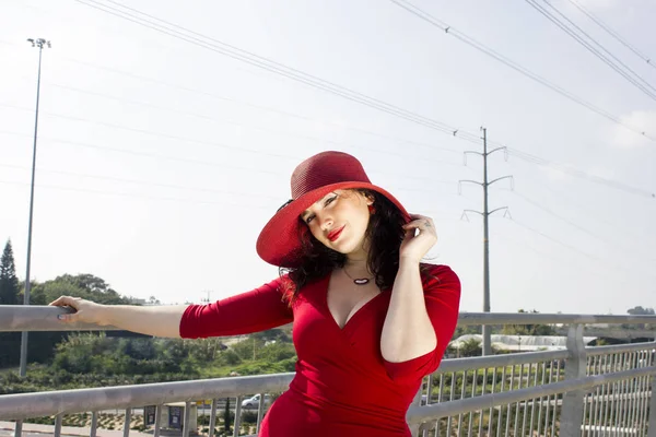 桥上穿着红衣服头戴红帽子的时尚女人的肖像 — 图库照片