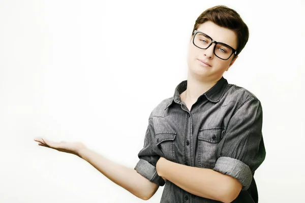 Hombre guapo en gafas y jeans camisa apuntando lejos y sonriendo, mientras que de pie sobre fondo blanco — Foto de Stock