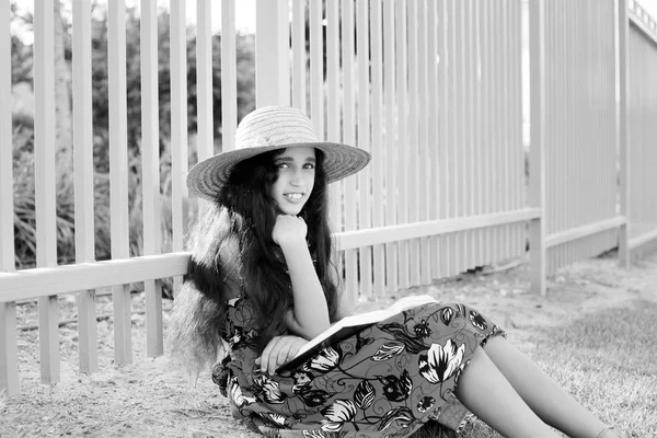 Entzückendes Mädchen in Kleid und Hut, das Buch liest. — Stockfoto