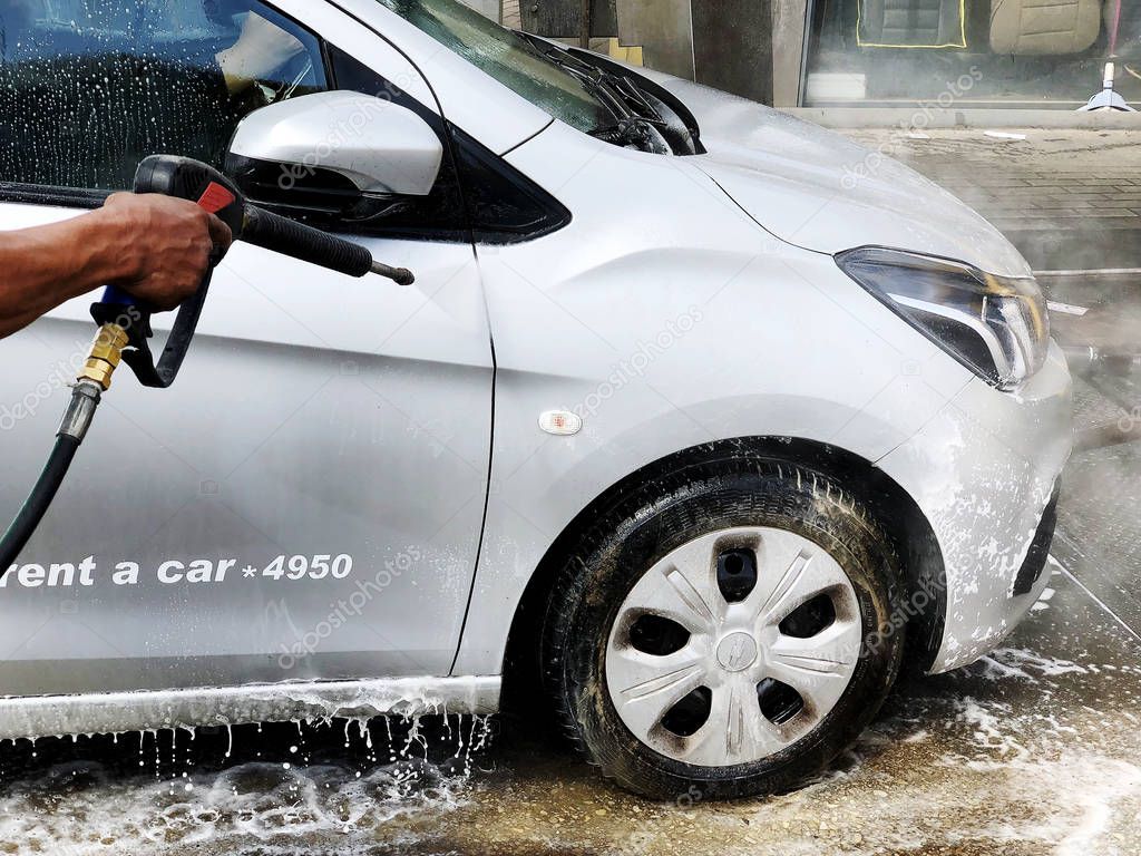 RISHON LE ZION, ISRAEL- FEBRUARY 27, 2018: Man wash a car by hand using a foam preparation for polishing, cars in a carwash