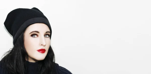 Portrait of young brunette woman posing in black winter hat on white background — Stock Photo, Image