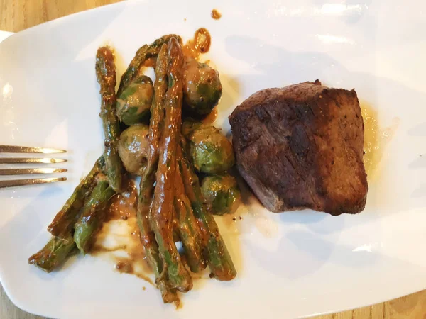 Grilled Beef Steak. Juicy beef steak. Gourmet steak with vegetables, grilled asparagus and brussels sprouts with sauce. — Stock Photo, Image