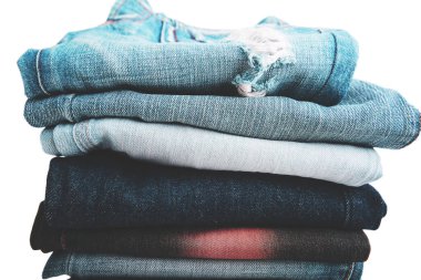 Beyaz arka plan üzerinde koyu mavi kot pantolon, kot pantolon ve katlanmış giysi yığını
