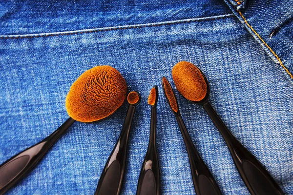 Professionell makeup borstar på denim bakgrund. Kvinnors tillbehör. — Stockfoto