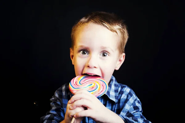 Niño sosteniendo piruleta sobre fondo negro — Foto de Stock