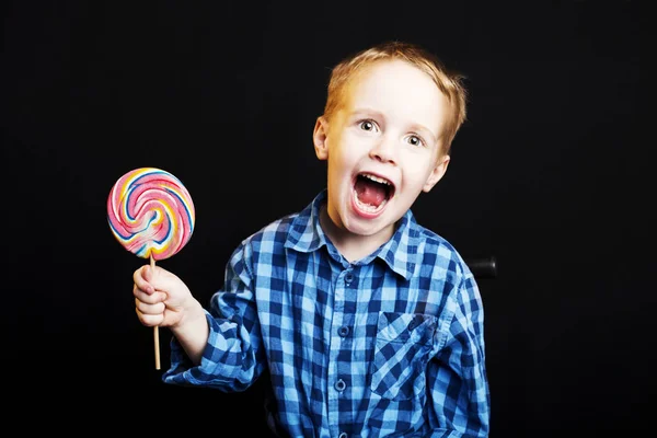 Young boy holding lollipop on black background — Stock Photo, Image