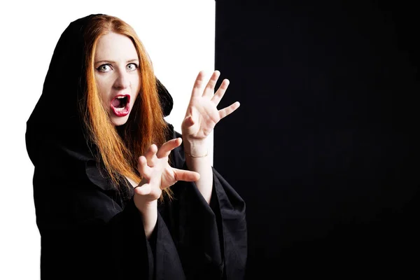 Beautiful redhead young pregnant woman in a black cloak with a hood. — Stock Photo, Image