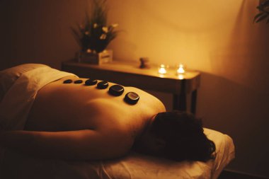 Adam bir spa siyah taşlar ile sırt üstü yatıyor