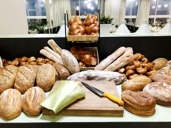 テーブルの上のパンと焼きたてのパンがたくさん。製パン事業。パン屋から種子を穀物から新鮮なパン. — ストック写真