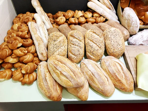 Un montón de pan fresco con bollos en la mesa. Un negocio de panes. Bollos frescos de cereales con semillas de una panadería . — Foto de Stock