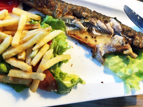 Много еды, жареной рыбы и жареной картошки на деревянном столе. Грузинская кухня — стоковое фото