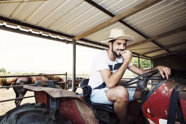 Joven agricultor sentado al volante de un viejo tractor . —  Fotos de Stock