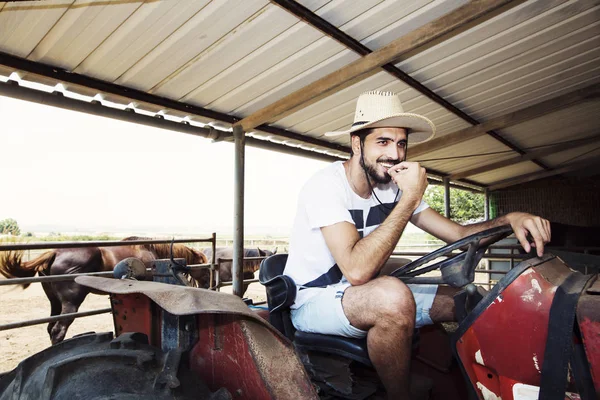 Jeune agriculteur assis au volant d'un vieux tracteur . — Photo