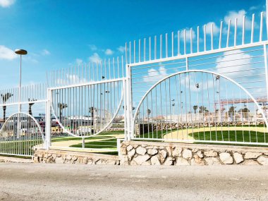 Nahariya, İsrail-Mart 9, 2018: Gökyüzü ve park güneşli bir günde. Rahatlama - bir park, park önünde beyaz bir çit için bir yer.