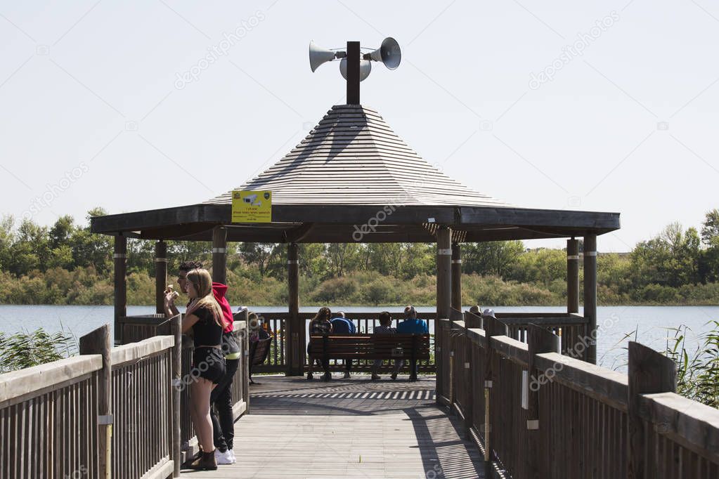 RISHON LE ZION, ISRAEL -APRIL 14, 2018: People walk along a wooden walking bridge near the lake in Rishon Lezion, Israel.