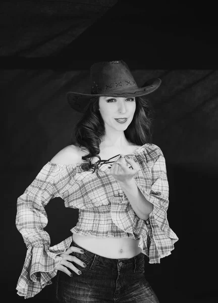 Belle cowgirl brune en chapeau de cow-boy sur fond sombre . — Photo