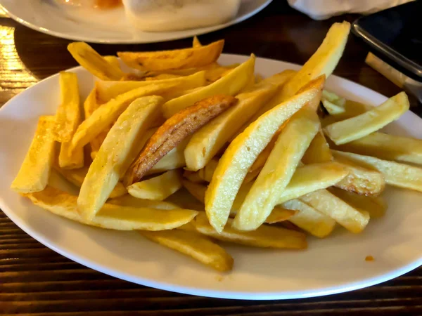 Batatas fritas no prato branco na mesa de madeira . — Fotografia de Stock