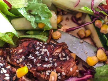 Tavuk biftek, salatalık, susam, Mısır sos ile yeşil yaprakları salata