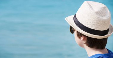 Dalgalar seyir hasır şapka ve güneş gözlüklü şirin çocuk çocuk portresi. Deniz kenarında tatil. Açık.