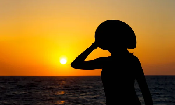 Silhouette lumineuse d'une femme en chapeau sur fond de coucher de soleil coloré et vif . — Photo