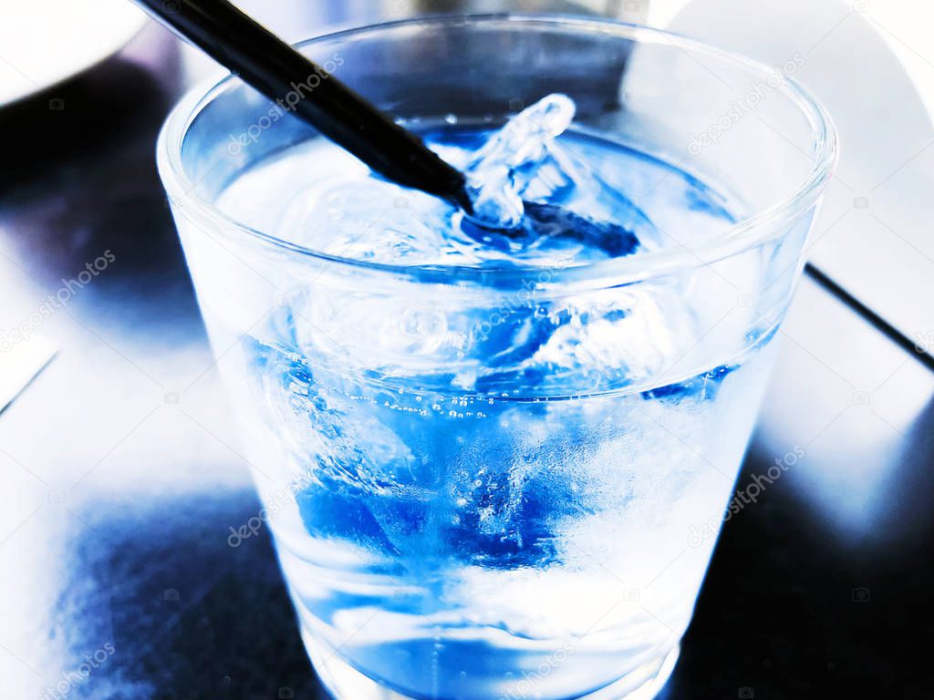 A glass of drinking water filled with ice on the wooden table