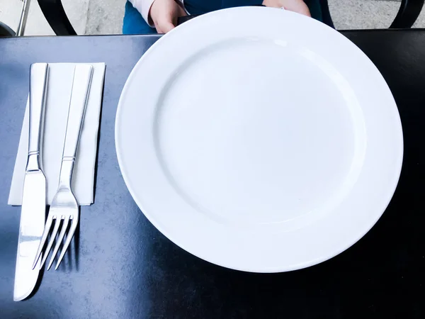 Plato blanco vacío sobre mesa negra con cuchillo y tenedor —  Fotos de Stock