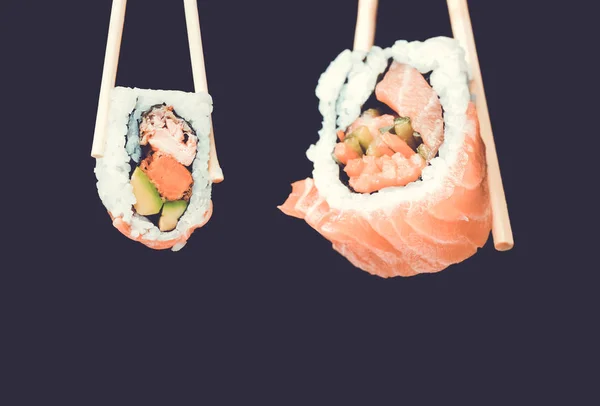 Sushi rolls holding by chopsticks. A traditional dish of Japanese cuisine. — Stock Photo, Image