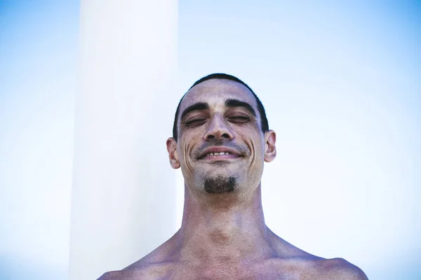 Joven musculoso en pantalones vaqueros descansando y posando en la playa — Foto de Stock