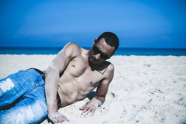 Joven musculoso descansando y posando en la playa . — Foto de Stock